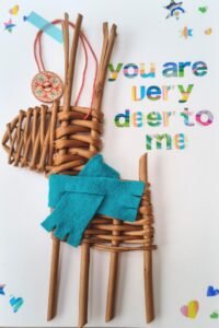a small deer made from orange /  brown willow with a teal scarf on a white card with colourful writing saying You are Deer to Me
