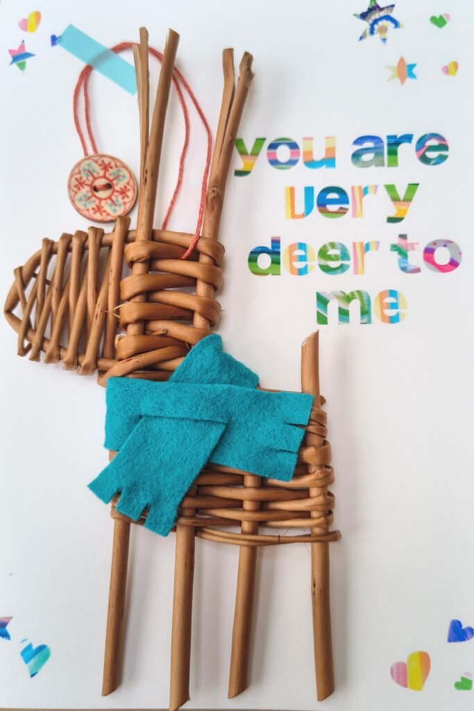 a small deer made from orange / brown willow with a teal scarf on a white card with colourful writing saying You are Deer to Me