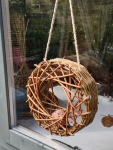 A circular bird feeders hanging from a window