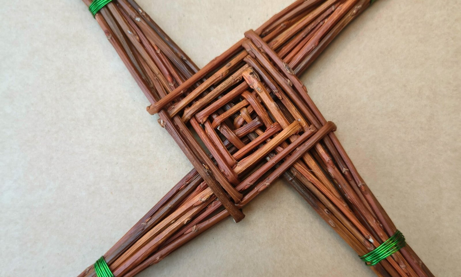 celtic cross made from brown willow, arms of the cross are bound with green wire