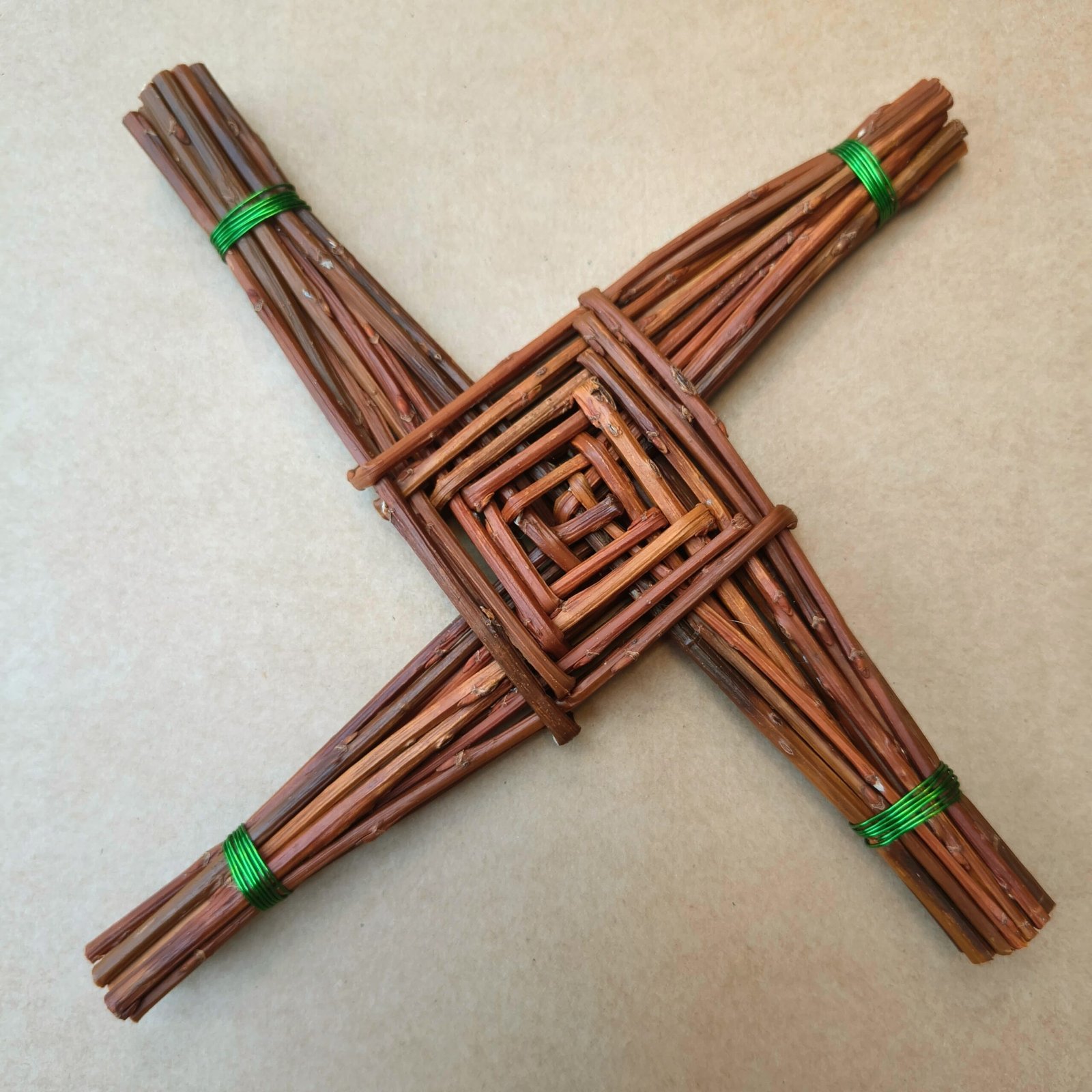 celtic cross made from brown willow, arms of the cross are bound with green wire